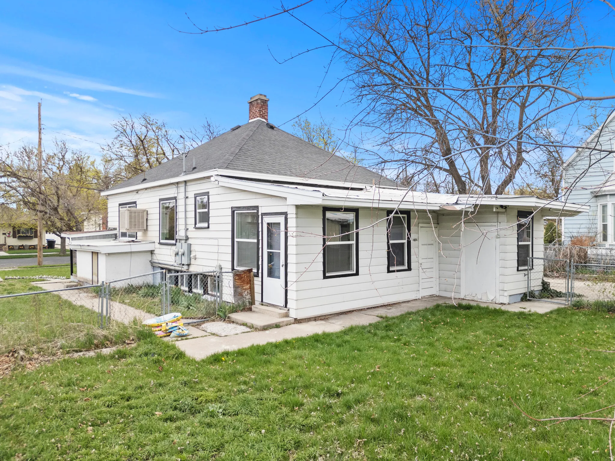 Back of property with a chimney, a gate, and roof with shingles