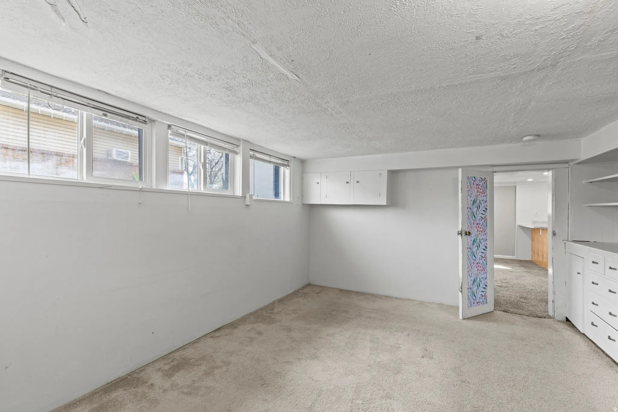 Basement featuring light carpet and a textured ceiling