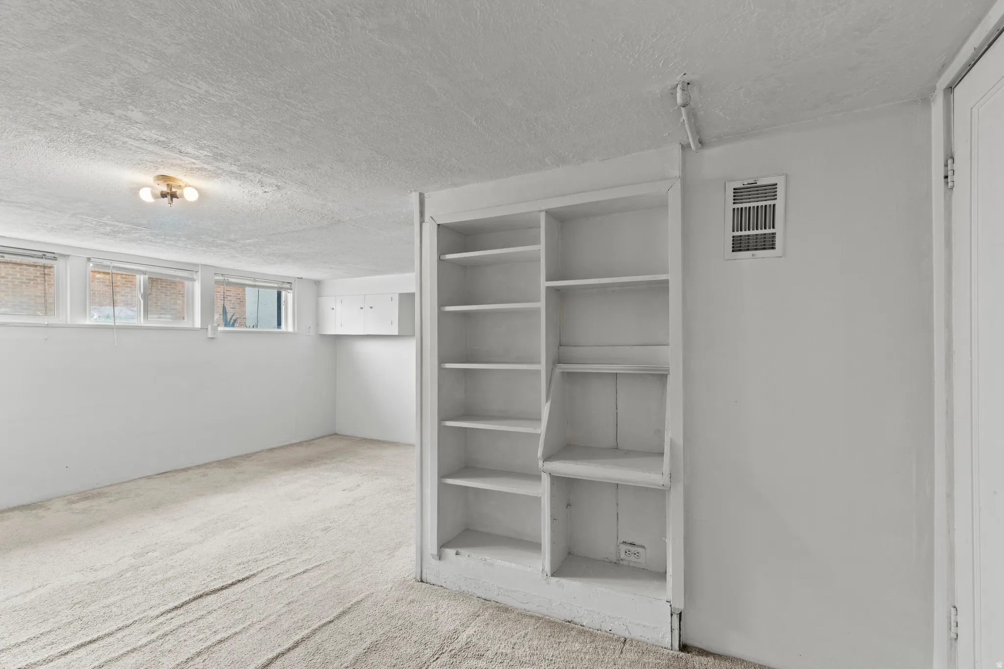 Below grade area featuring light colored carpet and a textured ceiling