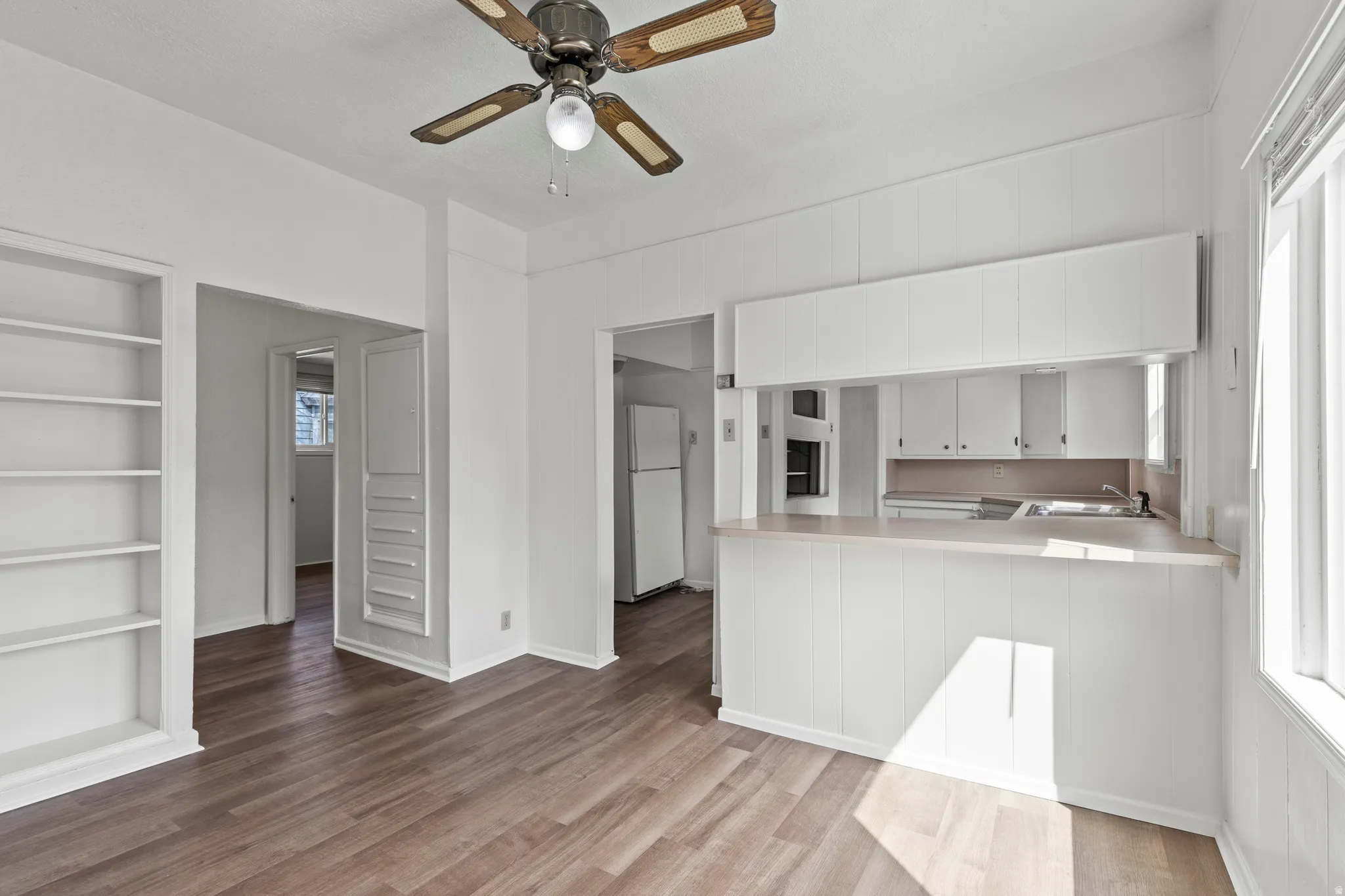 Kitchen featuring built in features, light countertops, freestanding refrigerator, and a peninsula