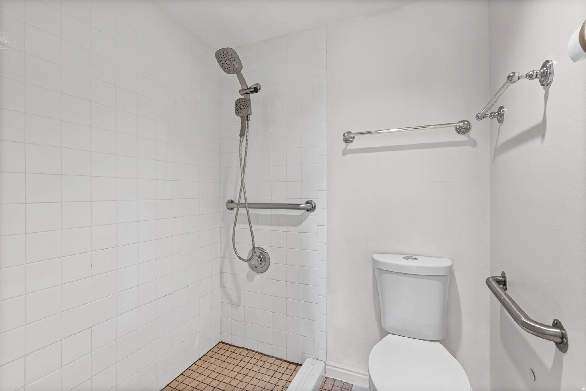 White subway tile shower surround with a handheld shower fixture