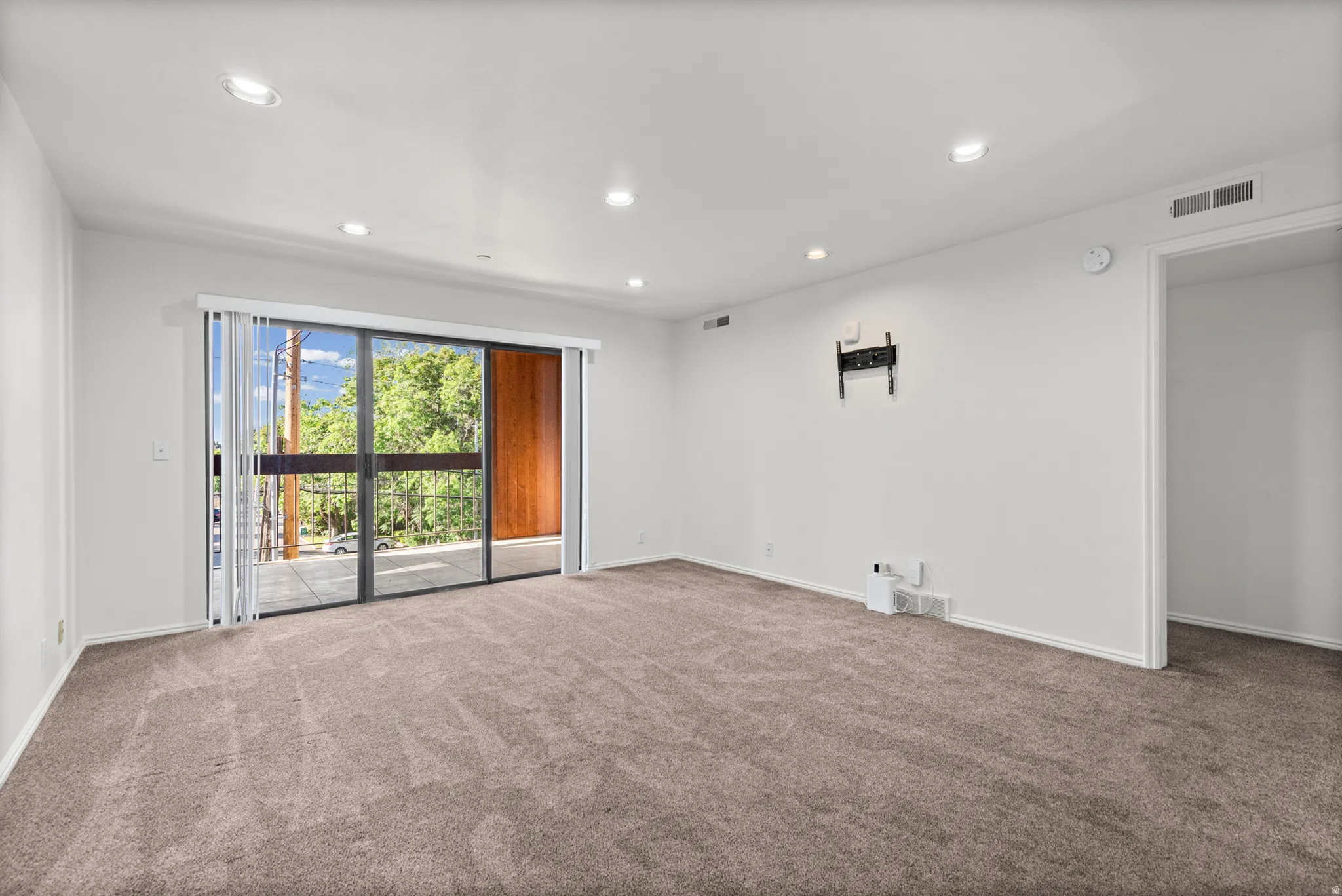 Recessed lighting and neutral carpeting complement the spacious room