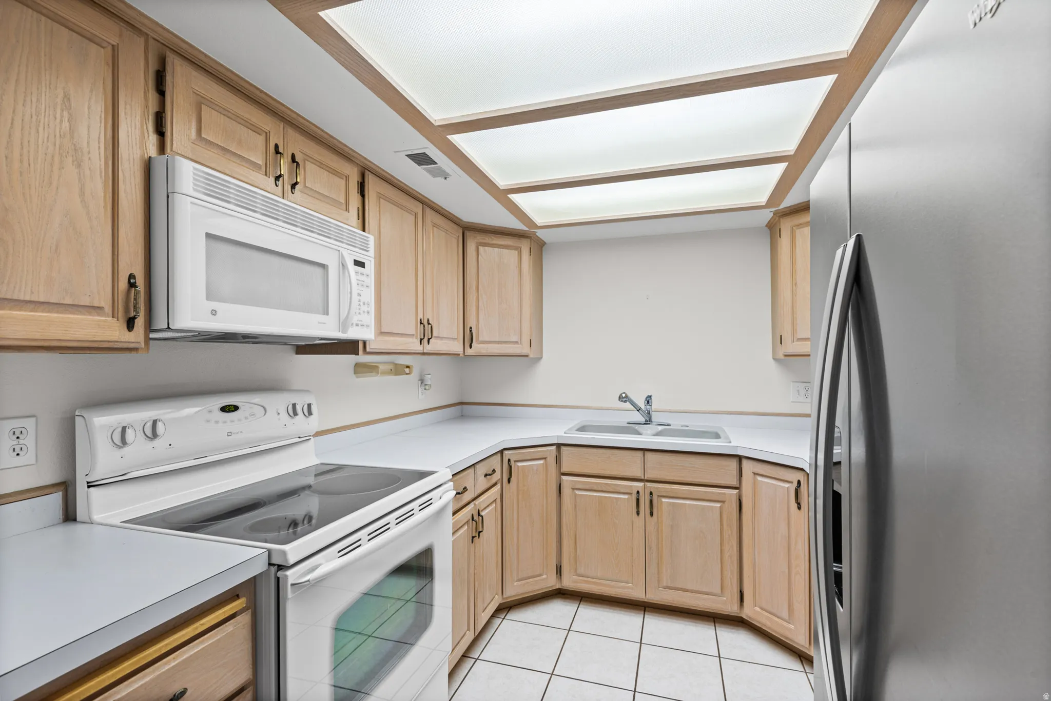 Kitchen with wood-finish cabinetry, integrated microwave, and white countertops