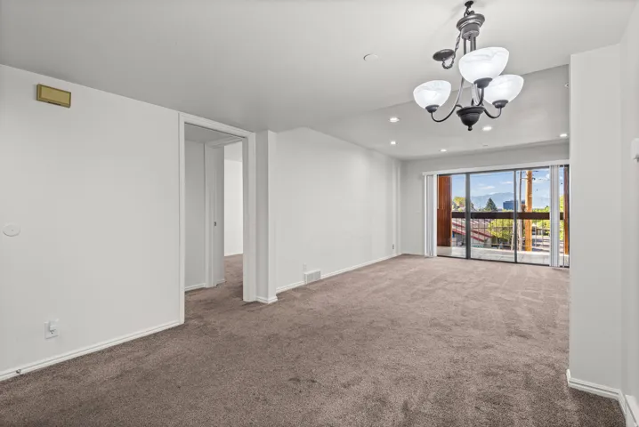 Expansive room with carpet flooring, a multi-globe chandelier, recessed lighting, and a large sliding glass door