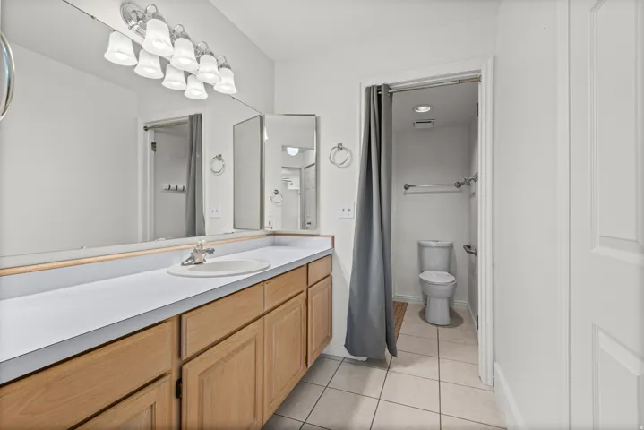 Extended vanity with wood-finish cabinetry, white countertop, and integrated sink