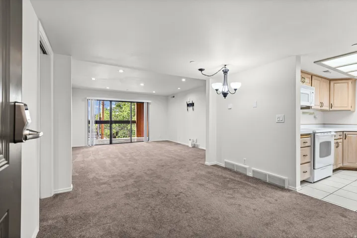 Spacious living area with sliding glass doors, recessed lighting, and carpet flooring