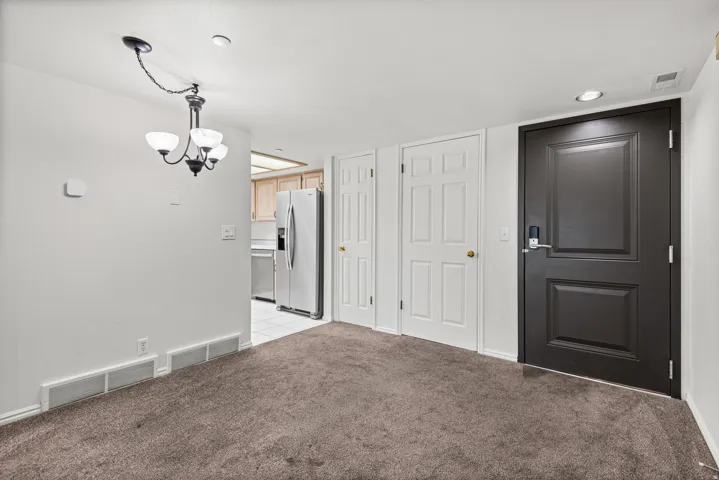 Recessed lighting, dark paneled entry door, white interior doors, three-light chandelier, and light-toned wall paint