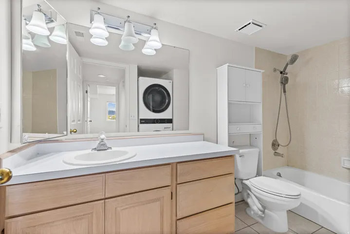 Bathroom featuring a single vanity, integrated sink, wood-finish cabinetry, and a full bathtub with a shower head