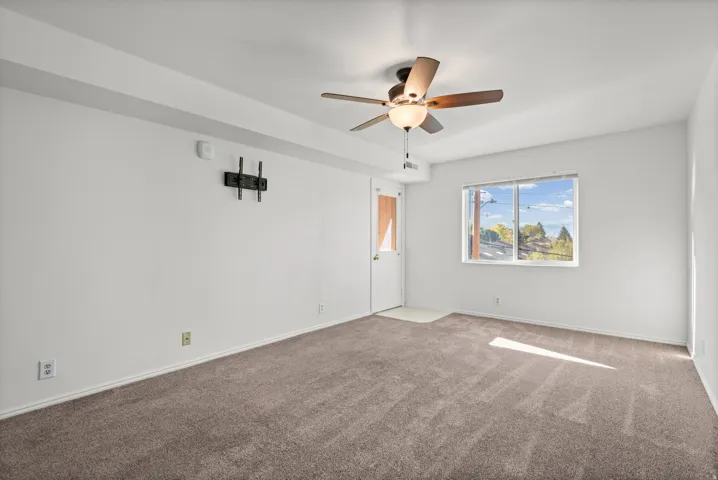 Carpeted interior with a ceiling fan, a window with outdoor scenery, and a wall-mounted bracket