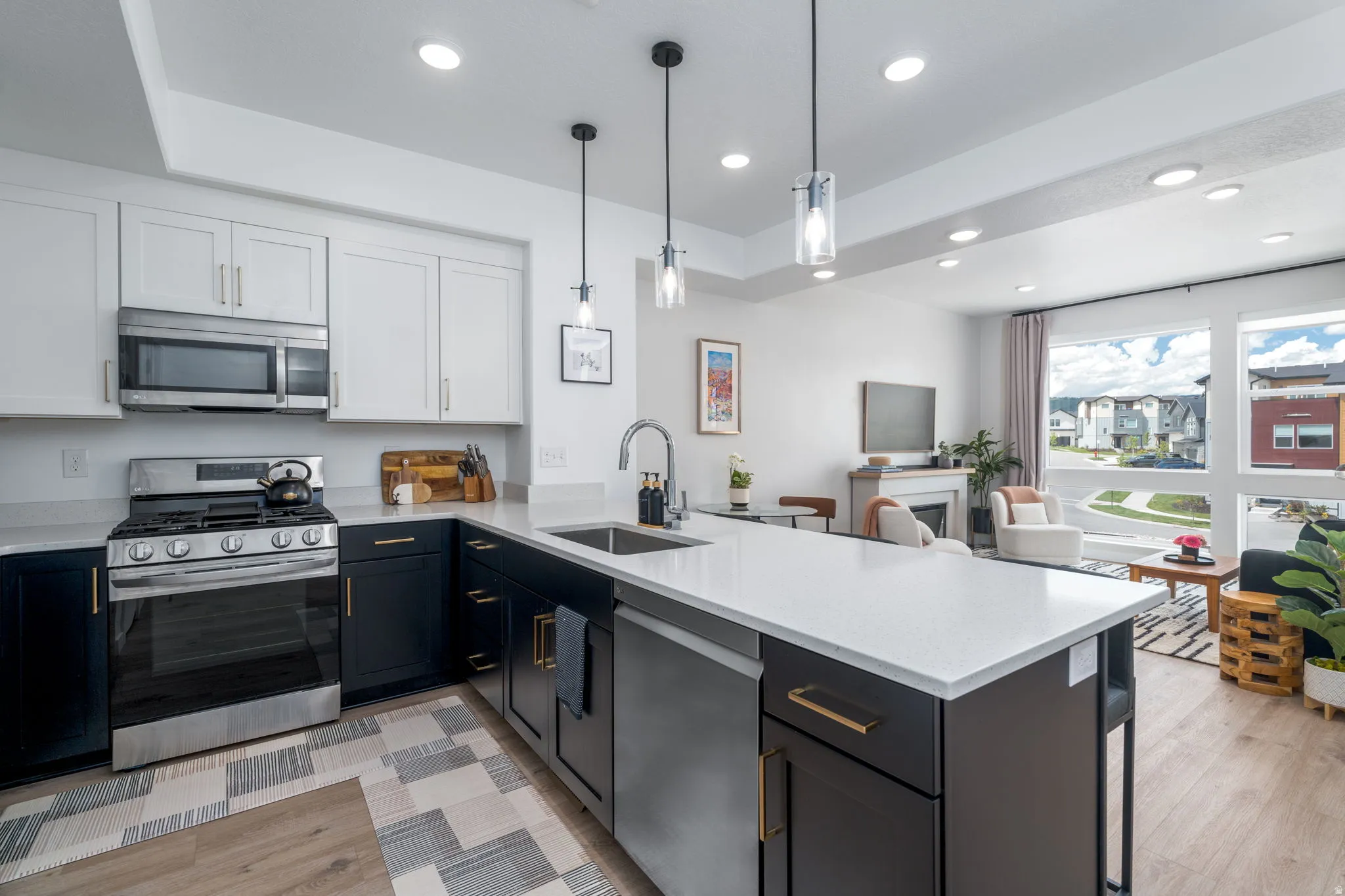 Kitchen featuring two tone cabinets, stainless steel appliances, a peninsula, light stone countertops, and a fireplace