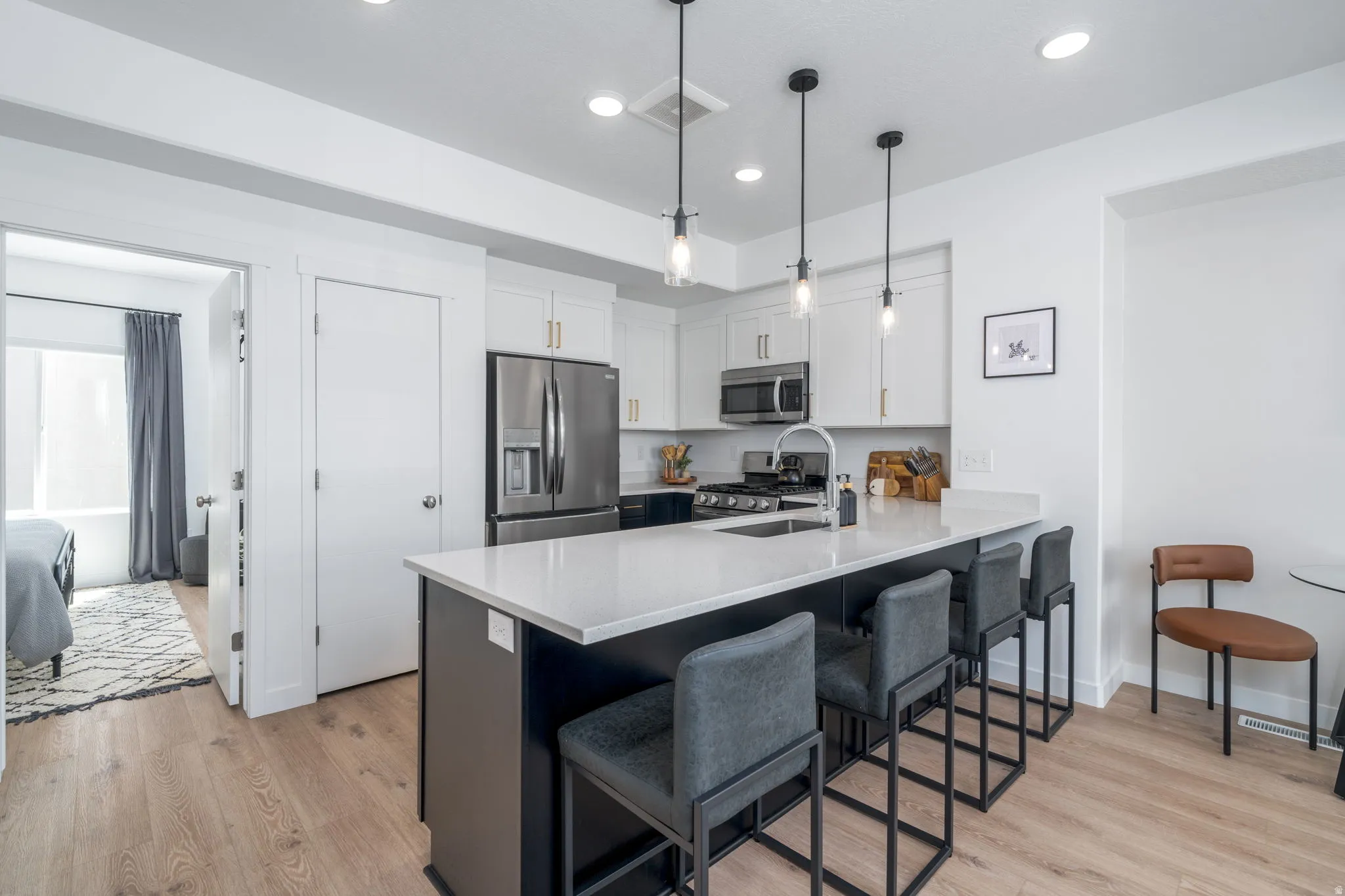 Dual tone kitchen featuring stainless steel appliances, a kitchen breakfast bar, a peninsula, light wood-style floors, and two tone cabinetry