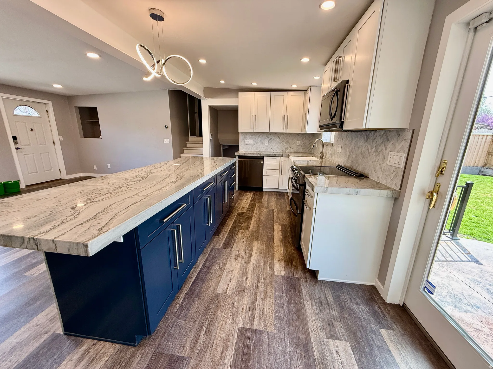 Two tone kitchen with two tone color scheme, double oven range, dark wood-style floors, pendant lighting, and black microwave