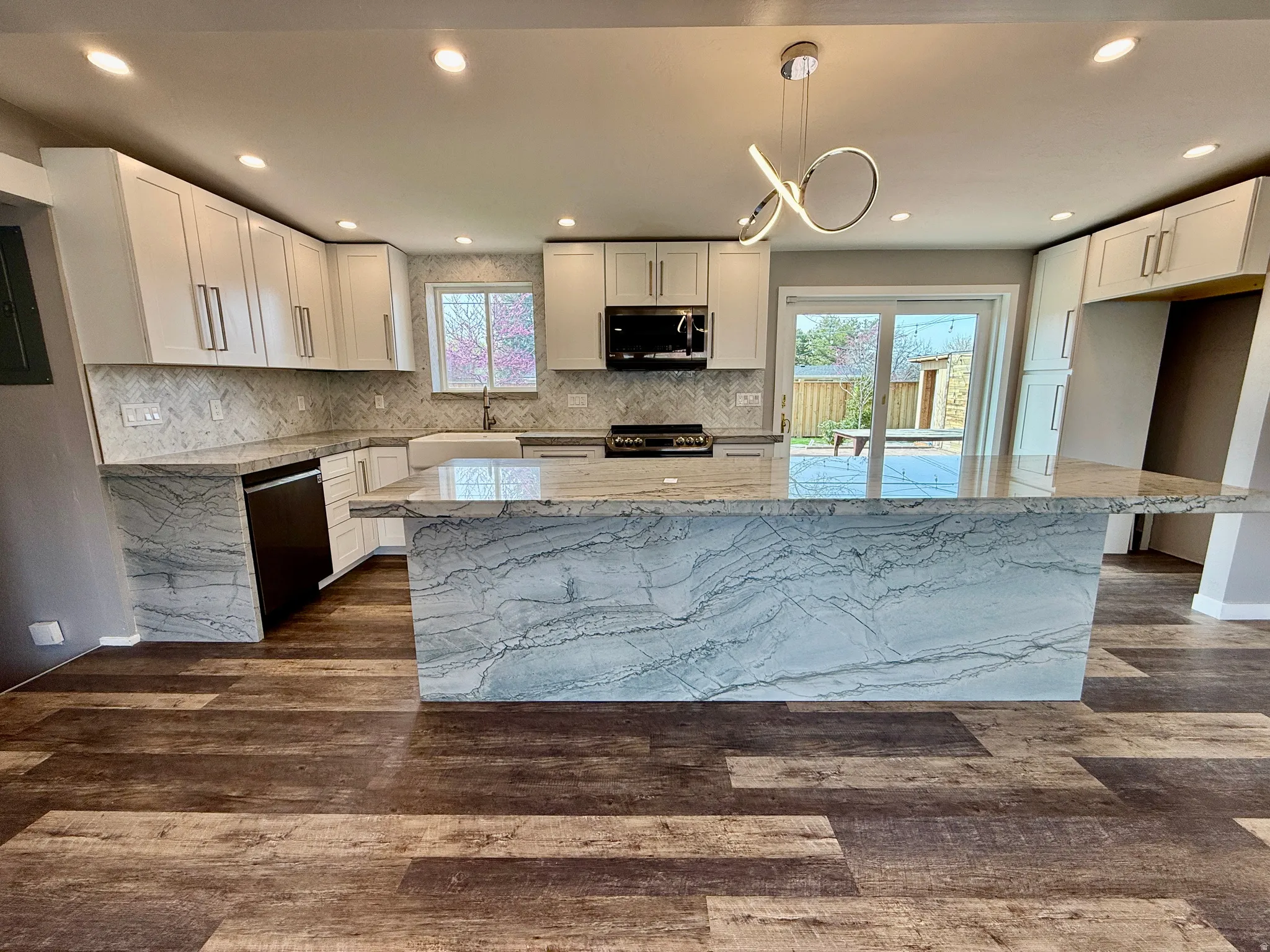 Kitchen featuring light stone counters, a kitchen island, dark wood-style floors, white cabinets, and stainless steel appliances