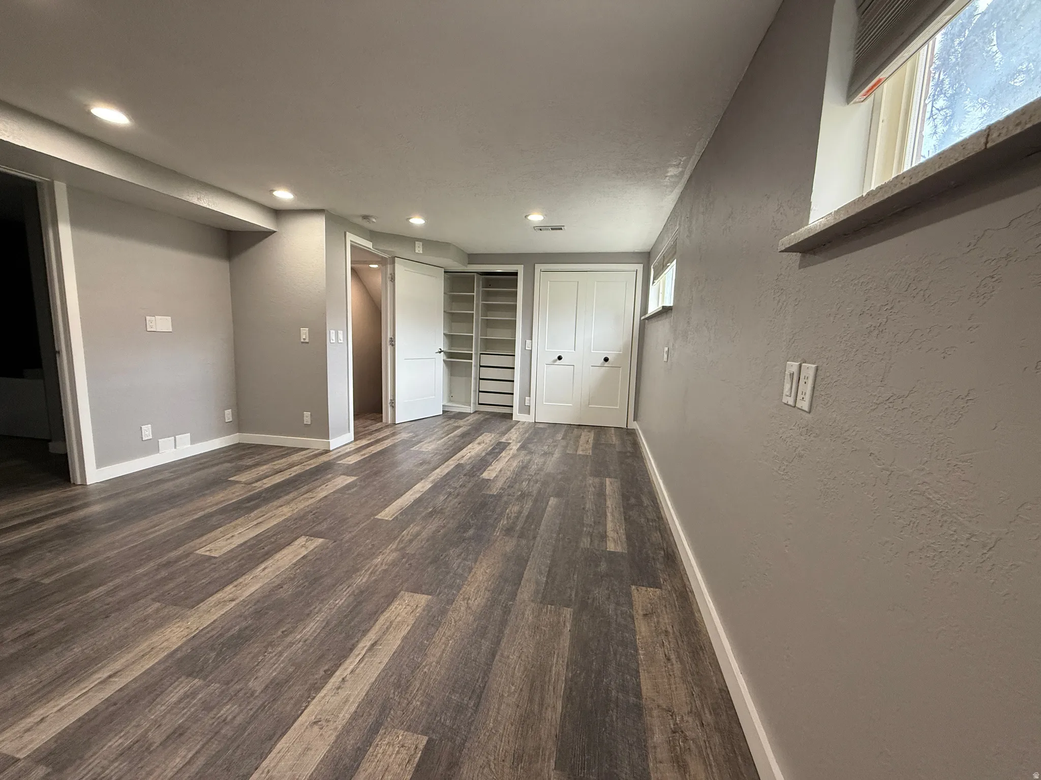 Master bedroom with dark wood-type flooring, a closet, and a textured wall