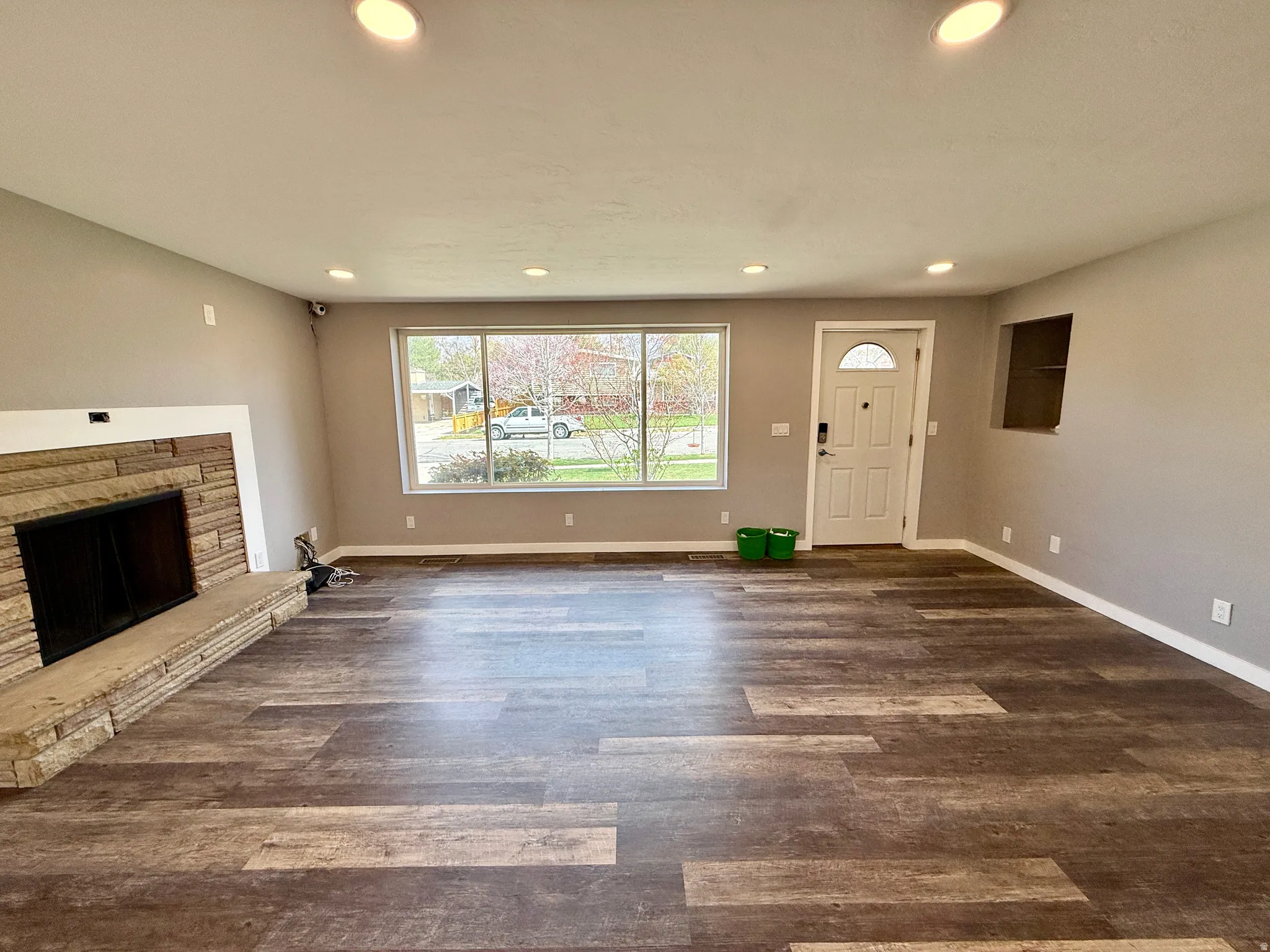 Unfurnished living room featuring dark wood-style flooring, a fireplace, and recessed lighting