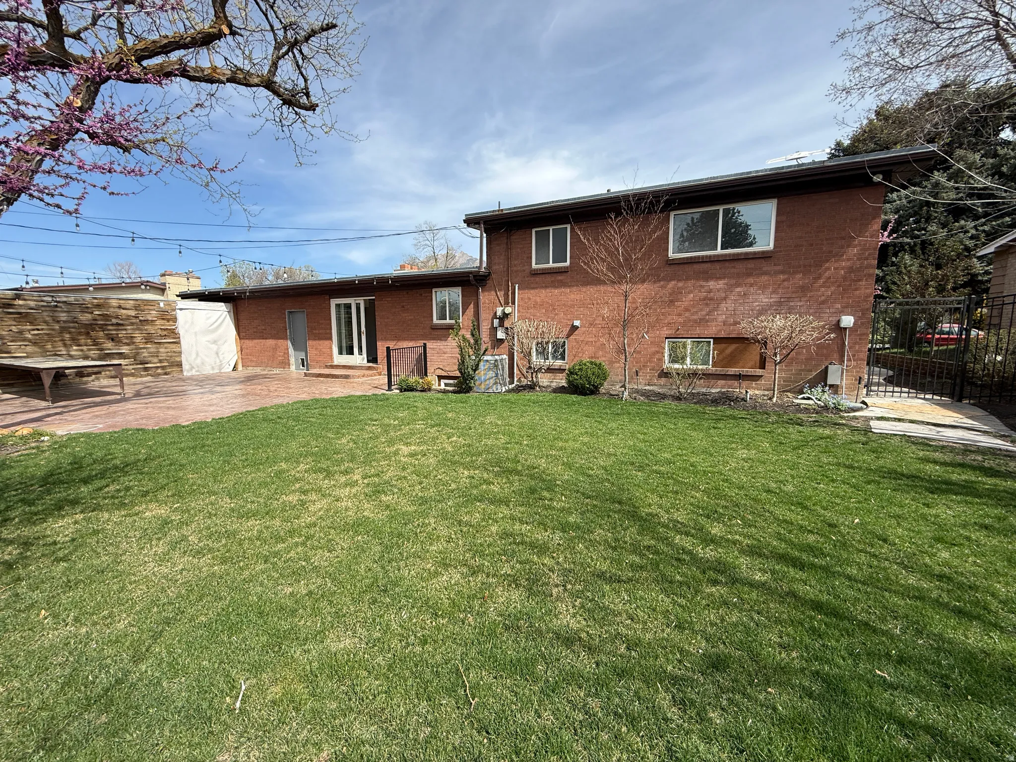 Back of house with brick siding, a patio area, and a gate
