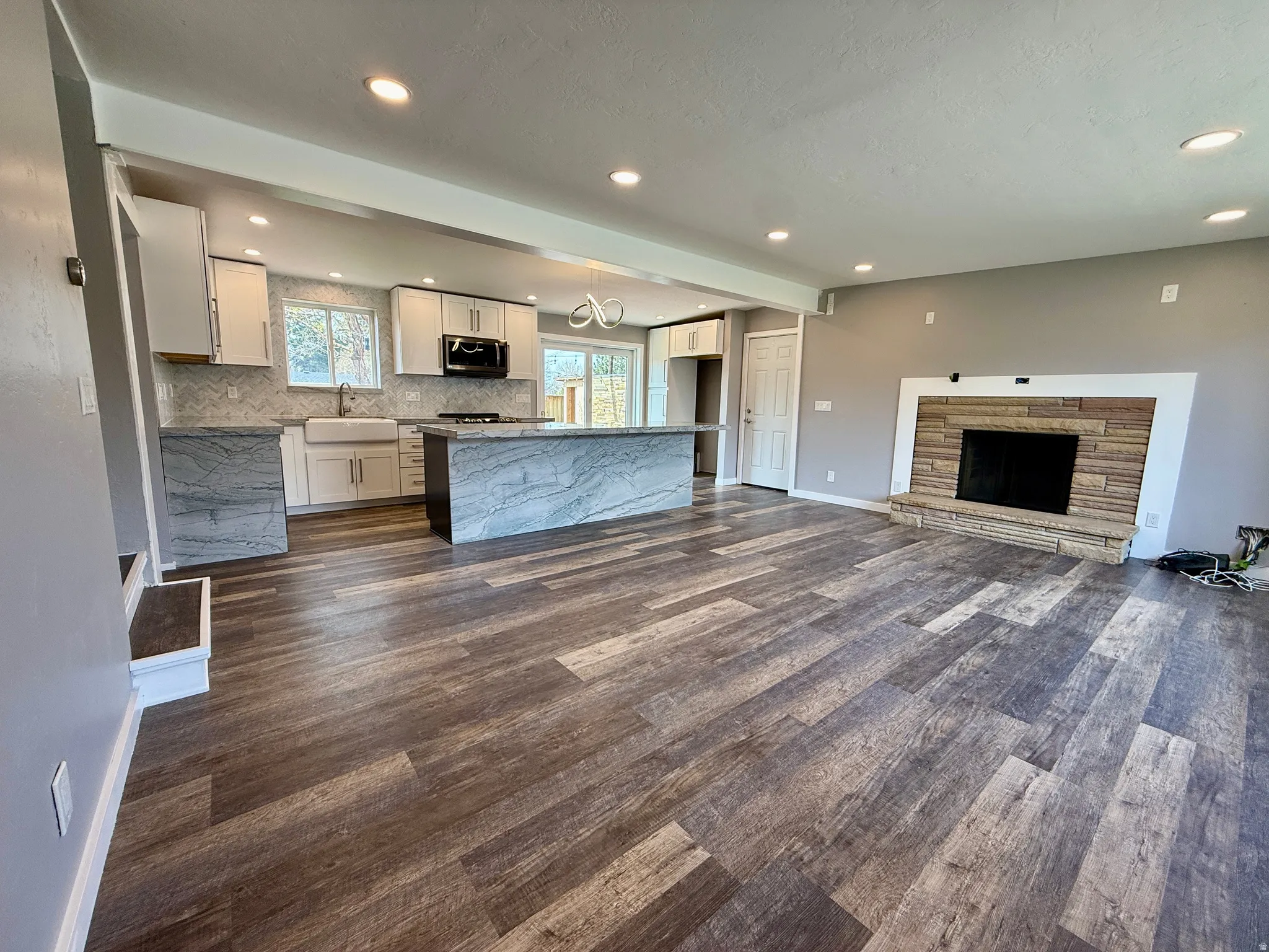 Unfurnished living room with dark wood-type flooring, recessed lighting, and a fireplace