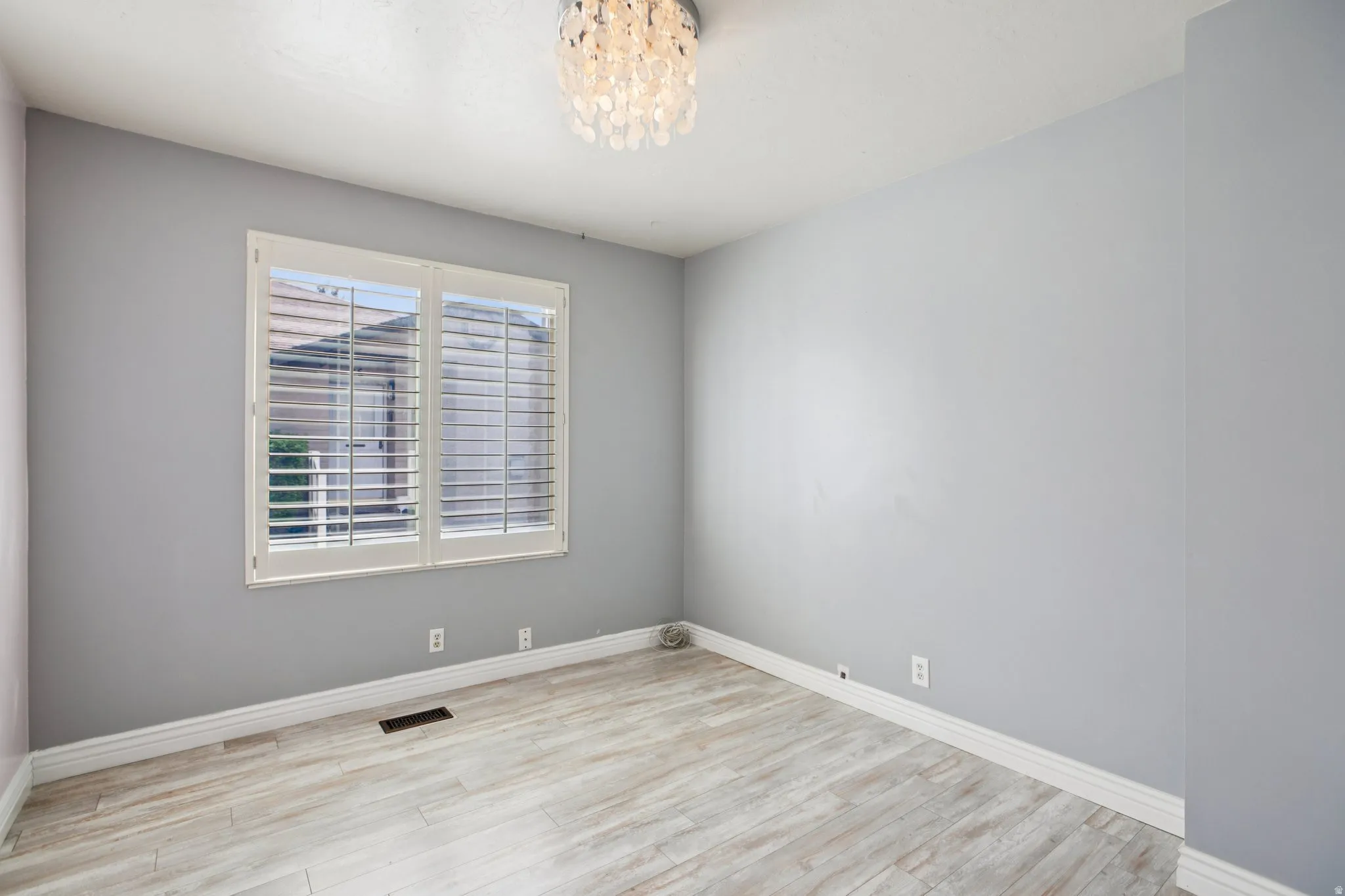 Empty room featuring light wood finished floors and a chandelier
