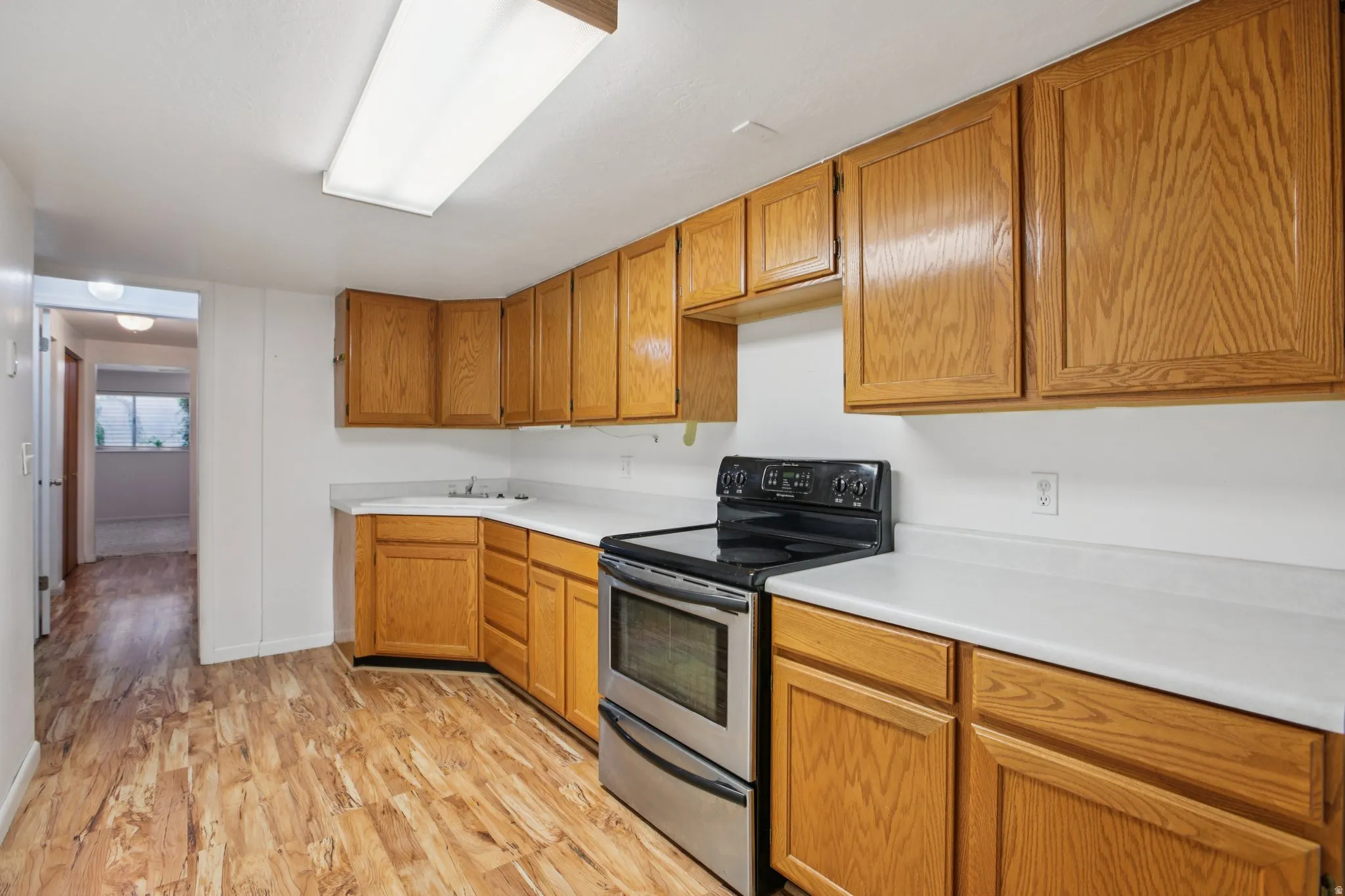Kitchen featuring electric stove, light countertops, light wood finished floors, and wood finish cabinetry