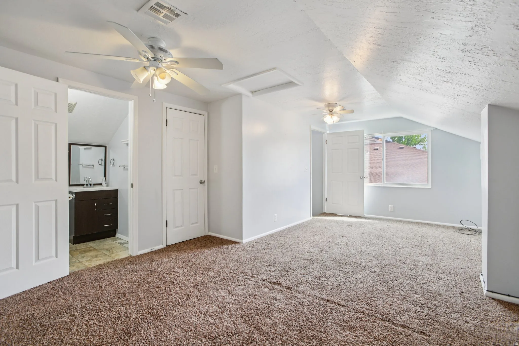 Bonus room with ceiling fan and light colored carpet