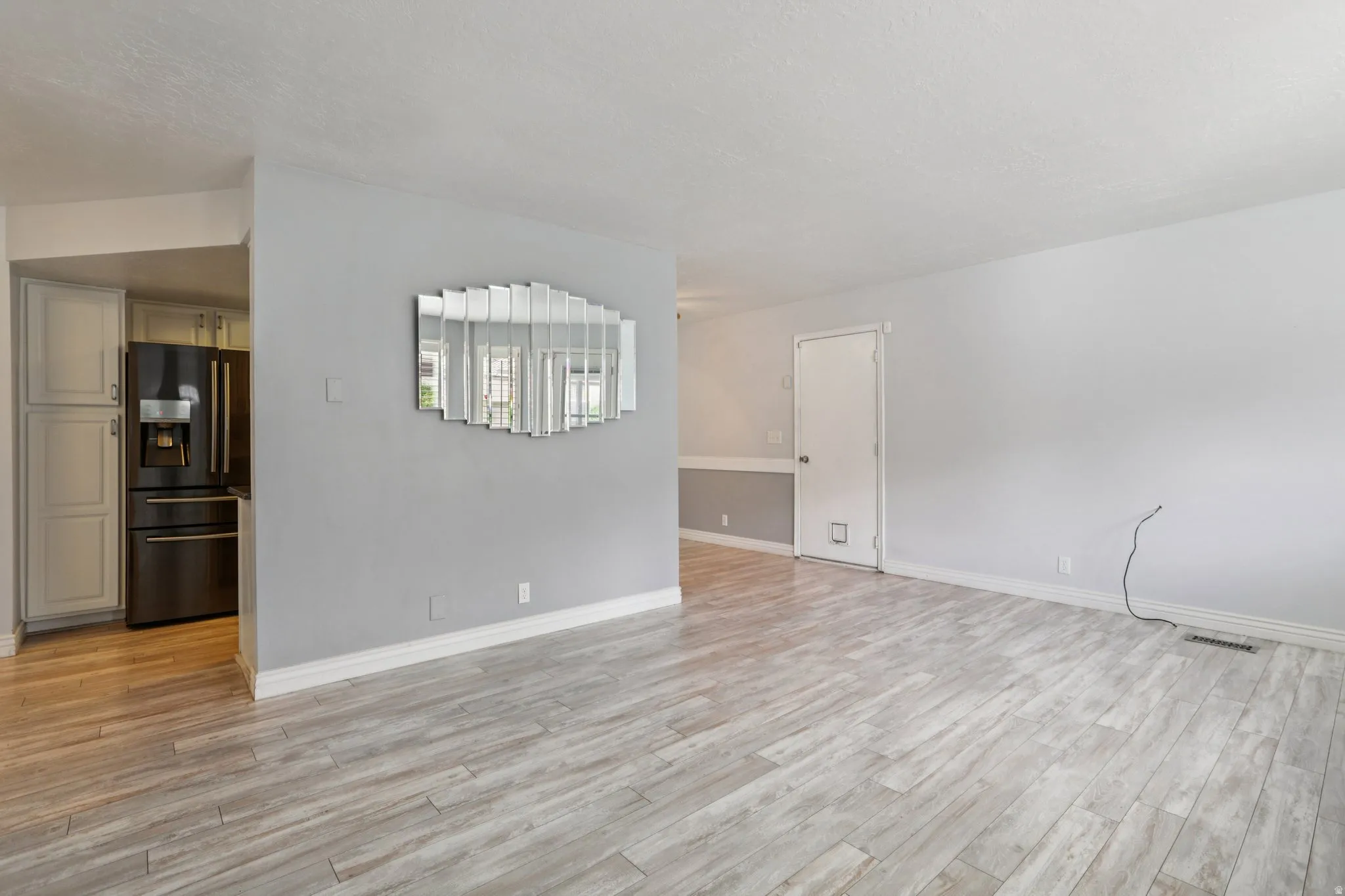 Empty room with light wood-type flooring and a textured ceiling
