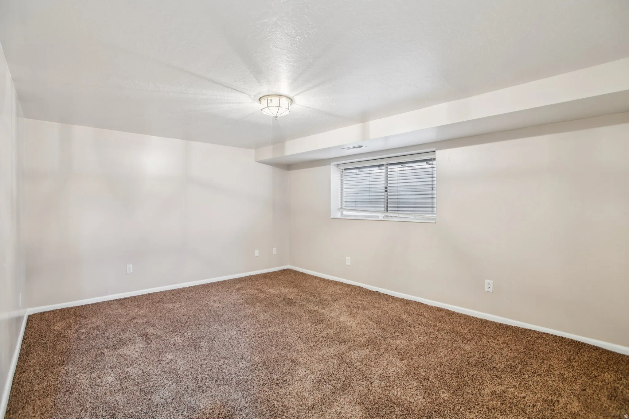 Spare room featuring baseboards and dark carpet