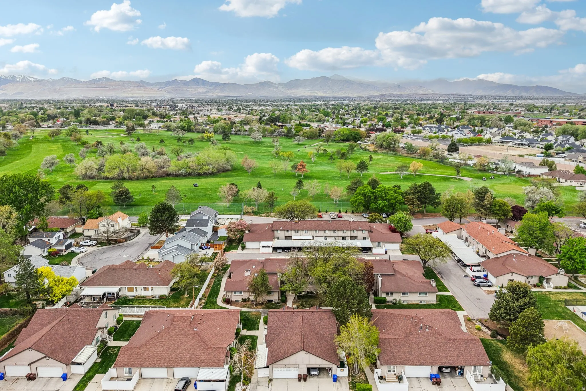Aerial perspective of suburban area featuring a local golf course and a mountainous background