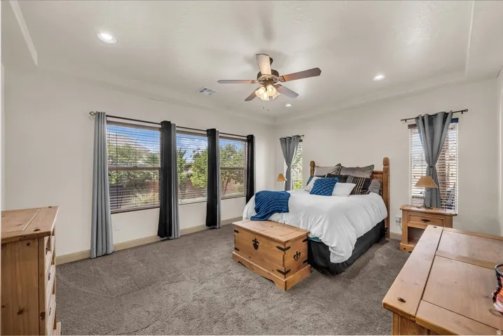 Primary bedroom featuring dark carpet, a ceiling fan, and recessed lighting