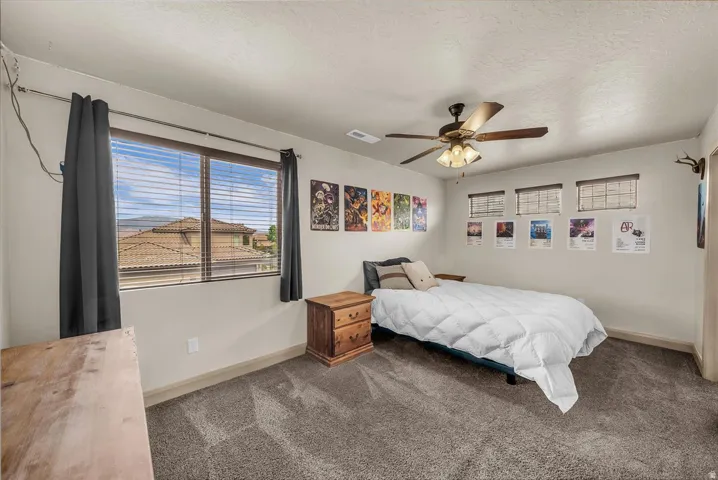 Carpeted bedroom featuring ceiling fan and a textured ceiling