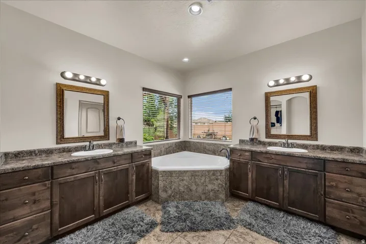 Primary bathroom featuring two vanities and a garden tub