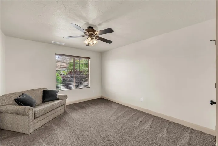 Unfurnished room with carpet, a ceiling fan, and a textured ceiling