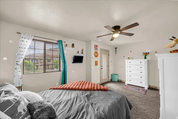 Bedroom featuring carpet floors, a ceiling fan, and a textured ceiling