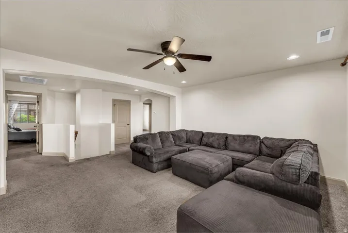 Carpeted living area featuring ceiling fan, recessed lighting, and arched walkways
