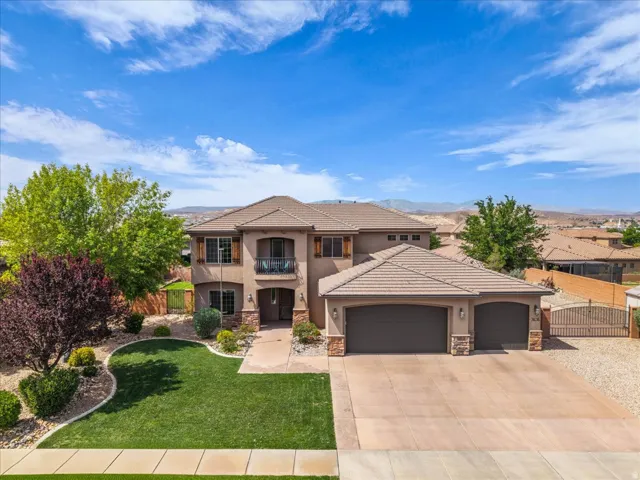 View of front of house with a balcony, an attached garage, stone siding, stucco siding, and driveway