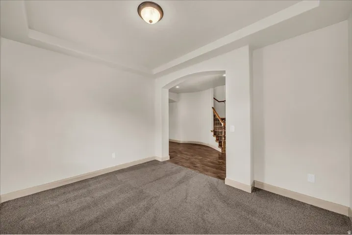 Empty room featuring arched walkways and carpet flooring