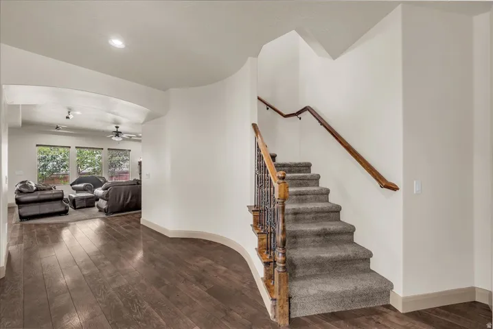 Staircase with wood-type flooring, ceiling fan, and recessed lighting