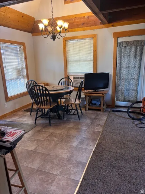 Dining area with lofted ceiling, hanging lights, cooling unit, and stone finish floors