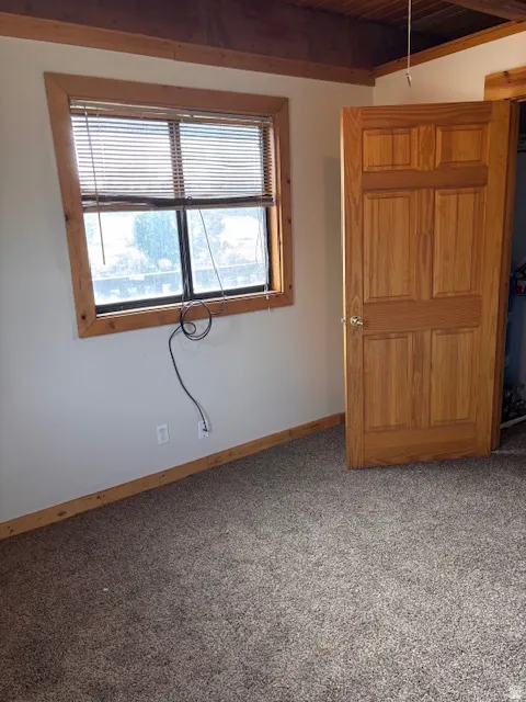 Empty room featuring light carpet and wood ceiling