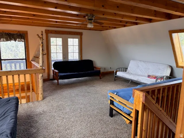 Living room with carpet floors, french doors, a ceiling fan, plenty of natural light, and beam ceiling