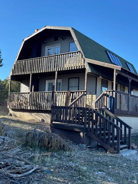 View of front of home with a gambrel roof and a balcony