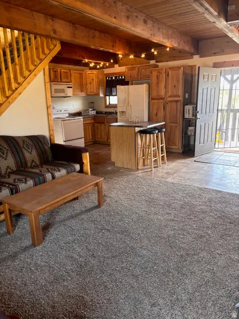 Living area featuring stairway and a wood ceiling with exposed beams