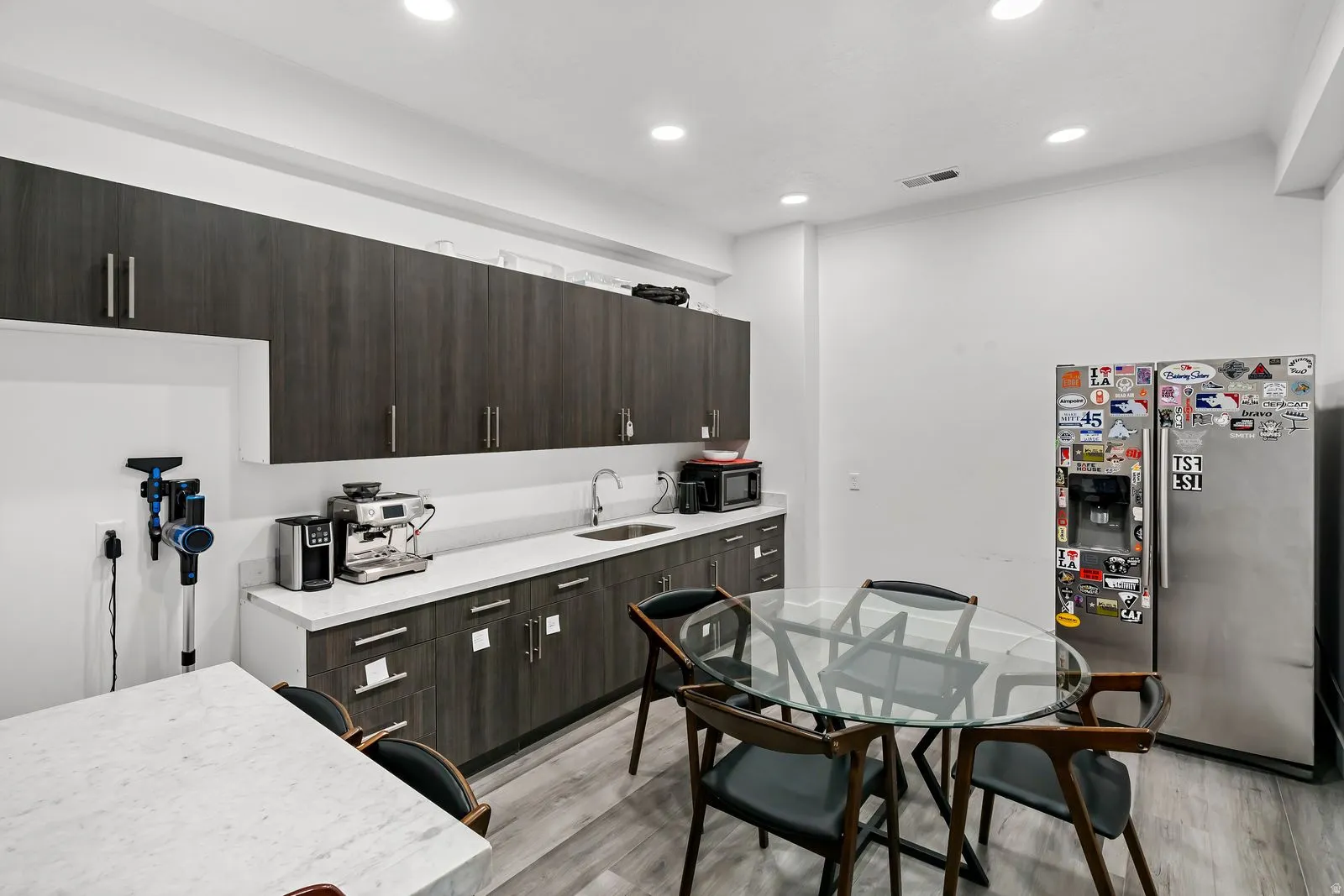 Kitchen featuring dark wood finish cabinets, stainless steel fridge with ice dispenser, modern cabinets, light wood finished floors, and recessed lighting
