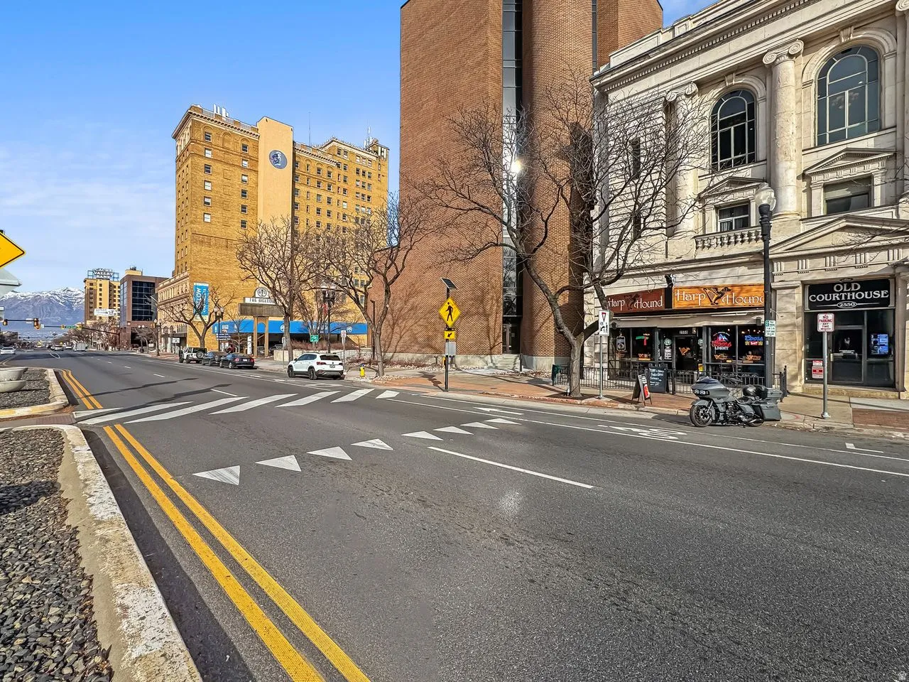 View of asphalt street with curbs, sidewalks, traffic signs, and street lights