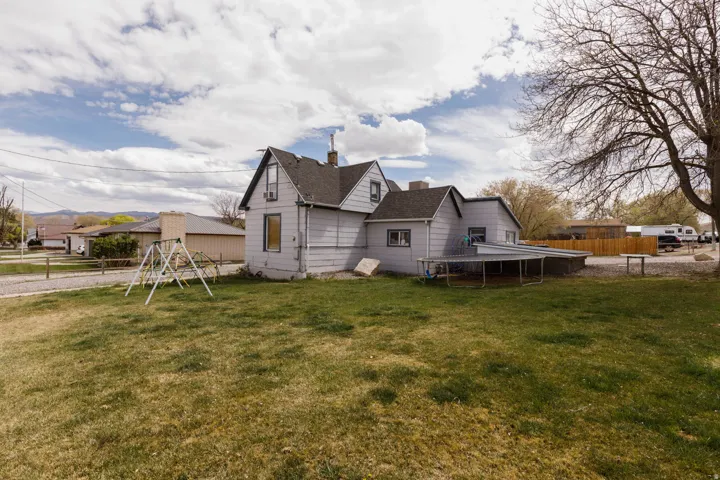 Back of house featuring a chimney, a playground, and a shingled roof