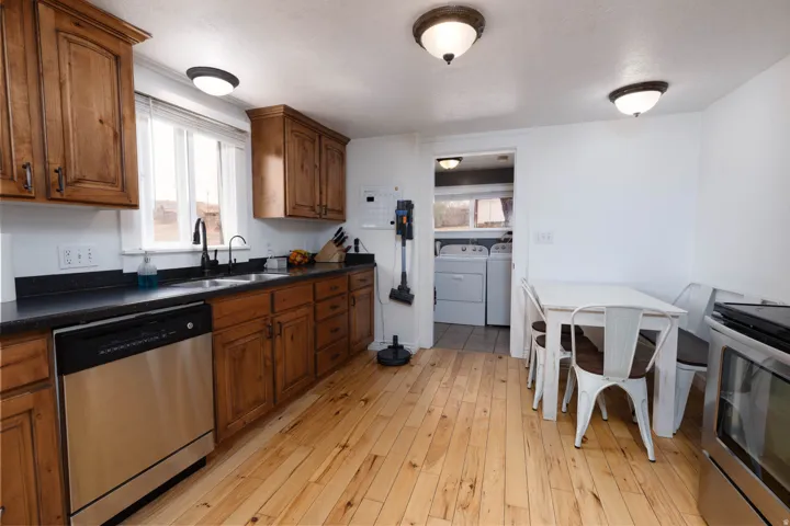 Kitchen with dark countertops, stainless steel appliances, independent washer and dryer, and wood finish cabinetry