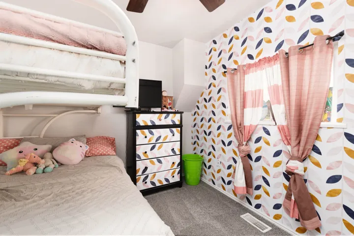 Bedroom featuring wallpapered walls, dark carpet, and a ceiling fan
