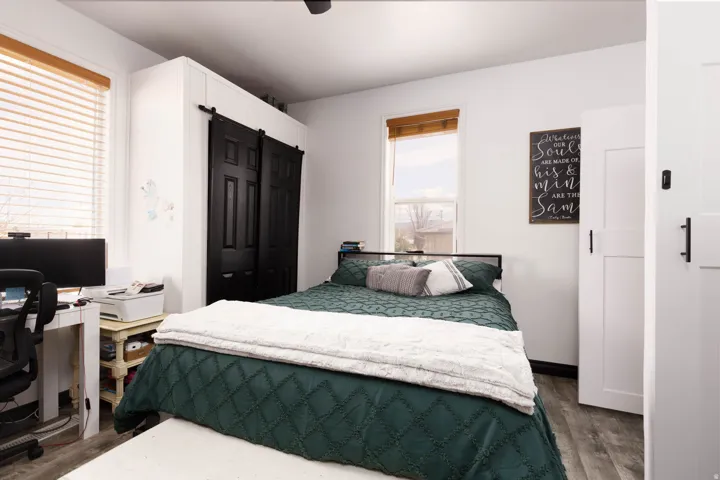 Bedroom featuring an office area, dark wood-type flooring, and ceiling fan