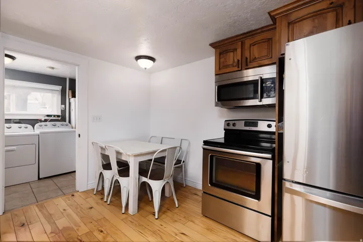 Kitchen featuring stainless steel appliances, washing machine and clothes dryer, a textured ceiling, and light wood finished floors