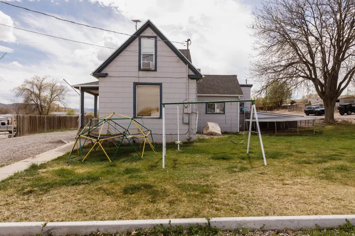 Rear view of house with a trampoline, a shingled roof, and a chimney