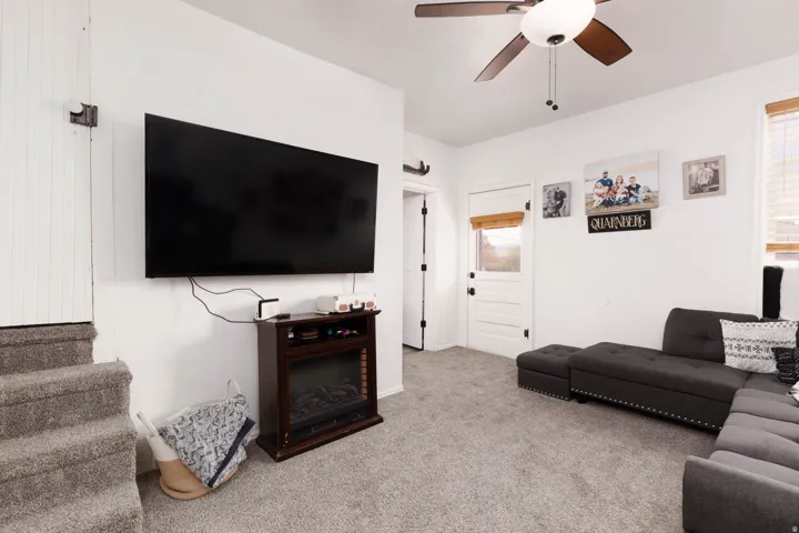 Carpeted living room featuring ceiling fan and healthy amount of natural light